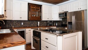 Una cocina con armarios blancos, un refrigerador de acero inoxidable, un microondas y un lavavajillas.