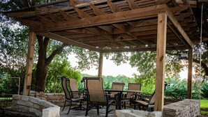 Un patio cubierto con escalones de piedra, pérgola de madera y mobiliario exterior.