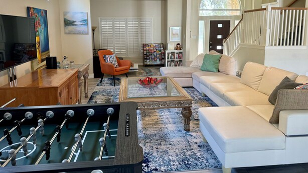 A living room with a foosball table, a sofa, a coffee table, and a TV.