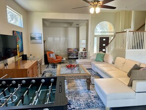 A living room with a foosball table, a sofa, a coffee table, and a TV. - Home Hidden In Plain Sight with HEATED Pool and Hot-Tub (San Antonio)