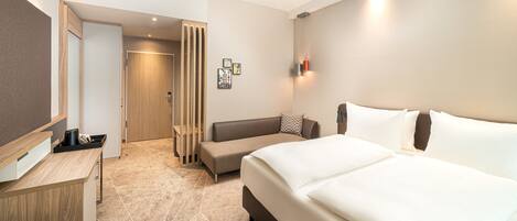 Une chambre d’hôtel comprenant un lit, un bureau, une chaise, un canapé et une salle de bain.