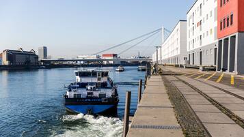 A river with a blue boat named "PILATOR" and a bridge in the background.