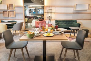 Un comedor con una mesa dispuesta para dos, sillas y un sofá verde.