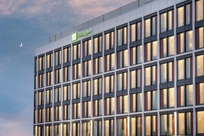 Un moderno edificio de hotel con un letrero llamativo, varias ventanas y un cielo despejado.
