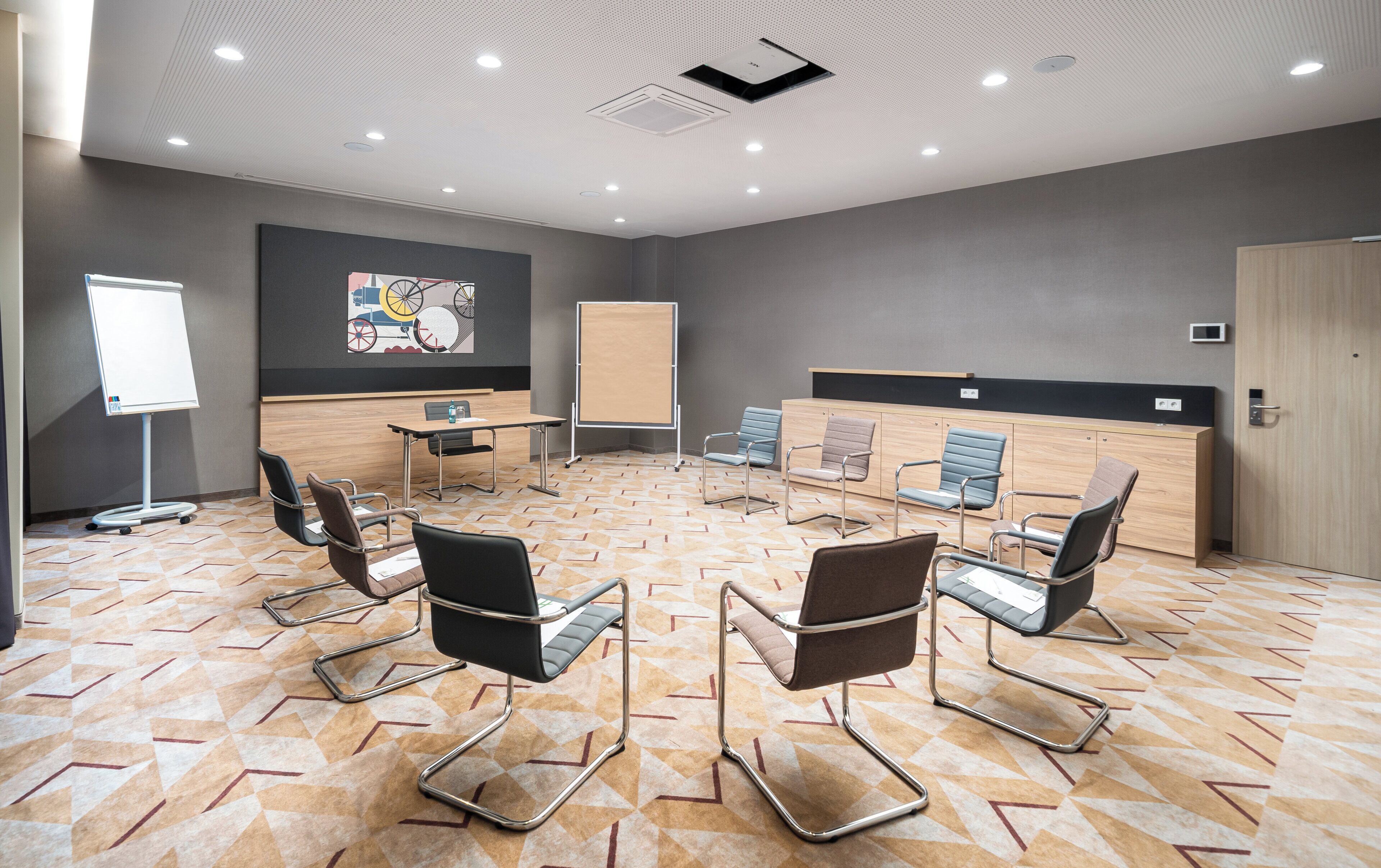 Une salle de conférence équipée d’une grande table, de plusieurs chaises, d’un tableau blanc et d’un comptoir d’accueil.