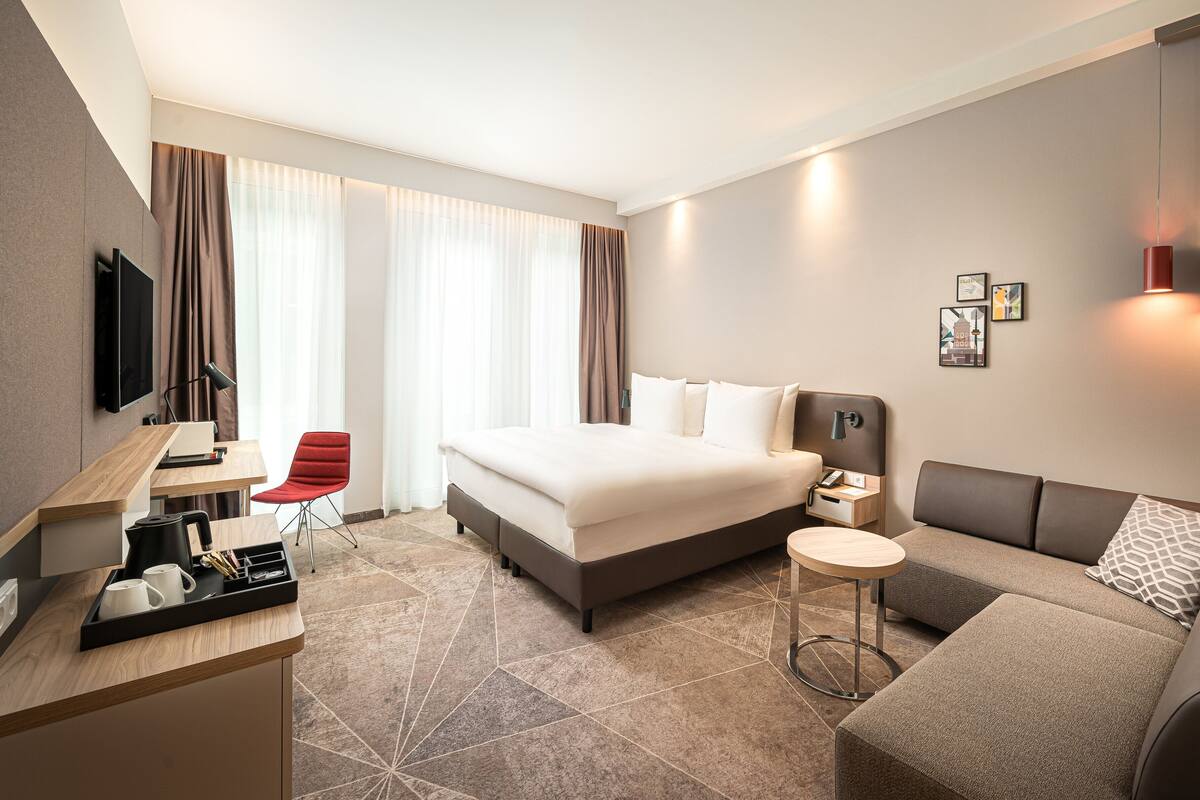 Ett modernt hotellrum med en stor säng, en soffa, ett skrivbord med en dator och en tv.
