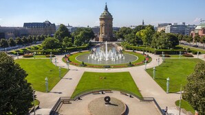 A large public square with a central fountain, surrounded by well-maintained lawns and a historic tower. - Holiday Inn Mannheim City - Hauptbahnhof by IHG (Mannheim)