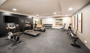 Un gimnasio con cintas de correr, bicicletas estáticas y máquinas de pesas.