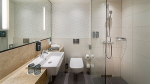 A modern bathroom with a glass-enclosed shower, a sink with a mirror, and a toilet. - Holiday Inn Mannheim City - Hauptbahnhof by IHG (Mannheim)