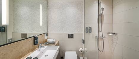 A modern bathroom with a glass-enclosed shower, a sink with a mirror, and a toilet.