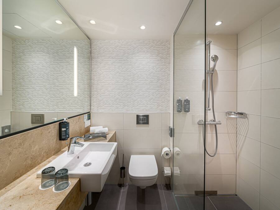 A modern bathroom with a glass-enclosed shower, a sink with a mirror, and a toilet.