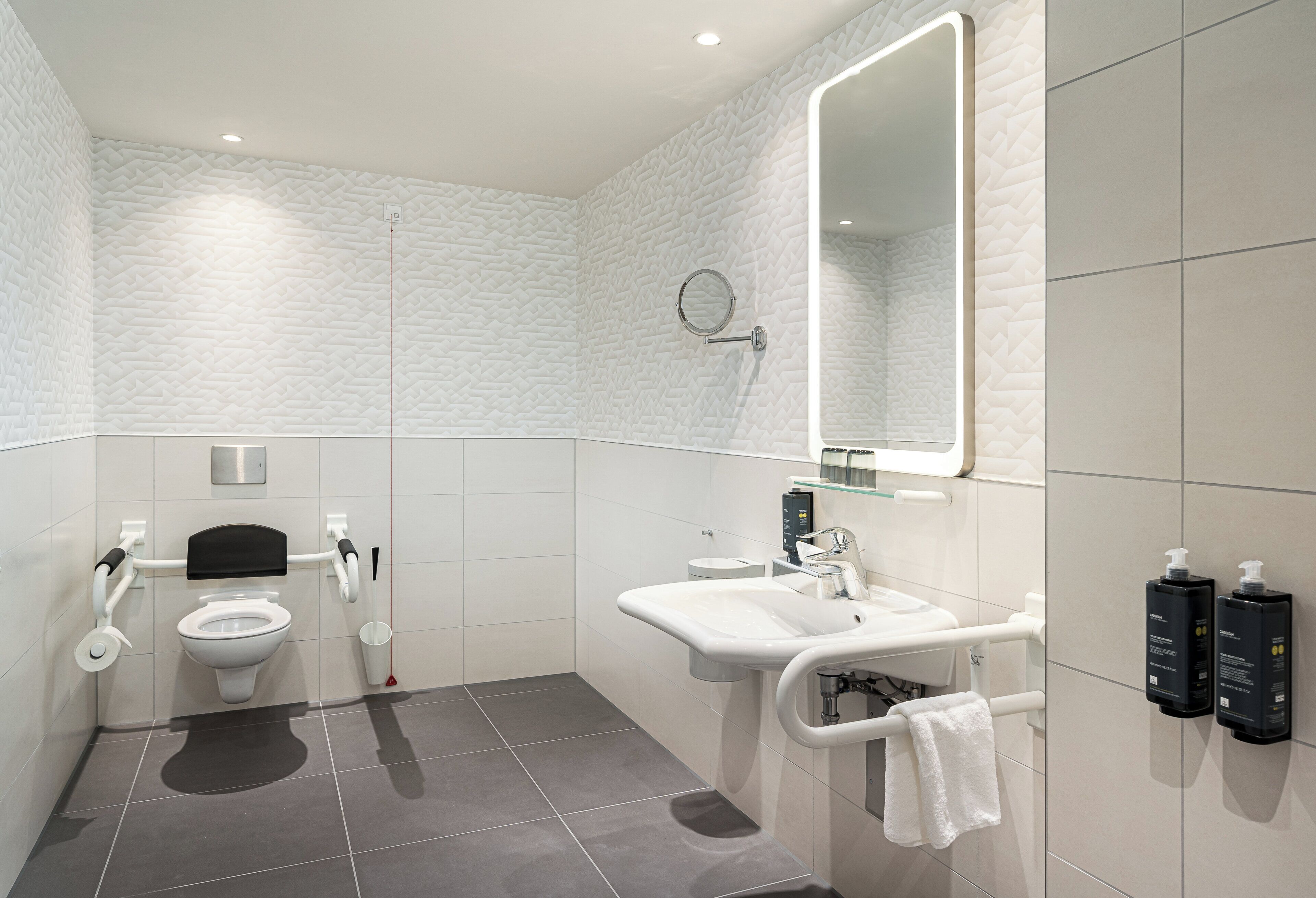 A modern bathroom with a toilet, sink, and mirror.