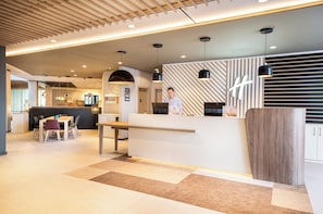 Un moderno vestíbulo de hotel con mostrador de recepción, zona de estar y un bar.