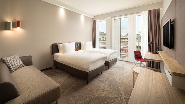 A hotel room with a bed, a sofa, a desk, and a TV. - Holiday Inn Mannheim City - Hauptbahnhof by IHG (Mannheim)