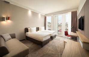Una habitación de hotel con cama, sofá, escritorio y televisión.