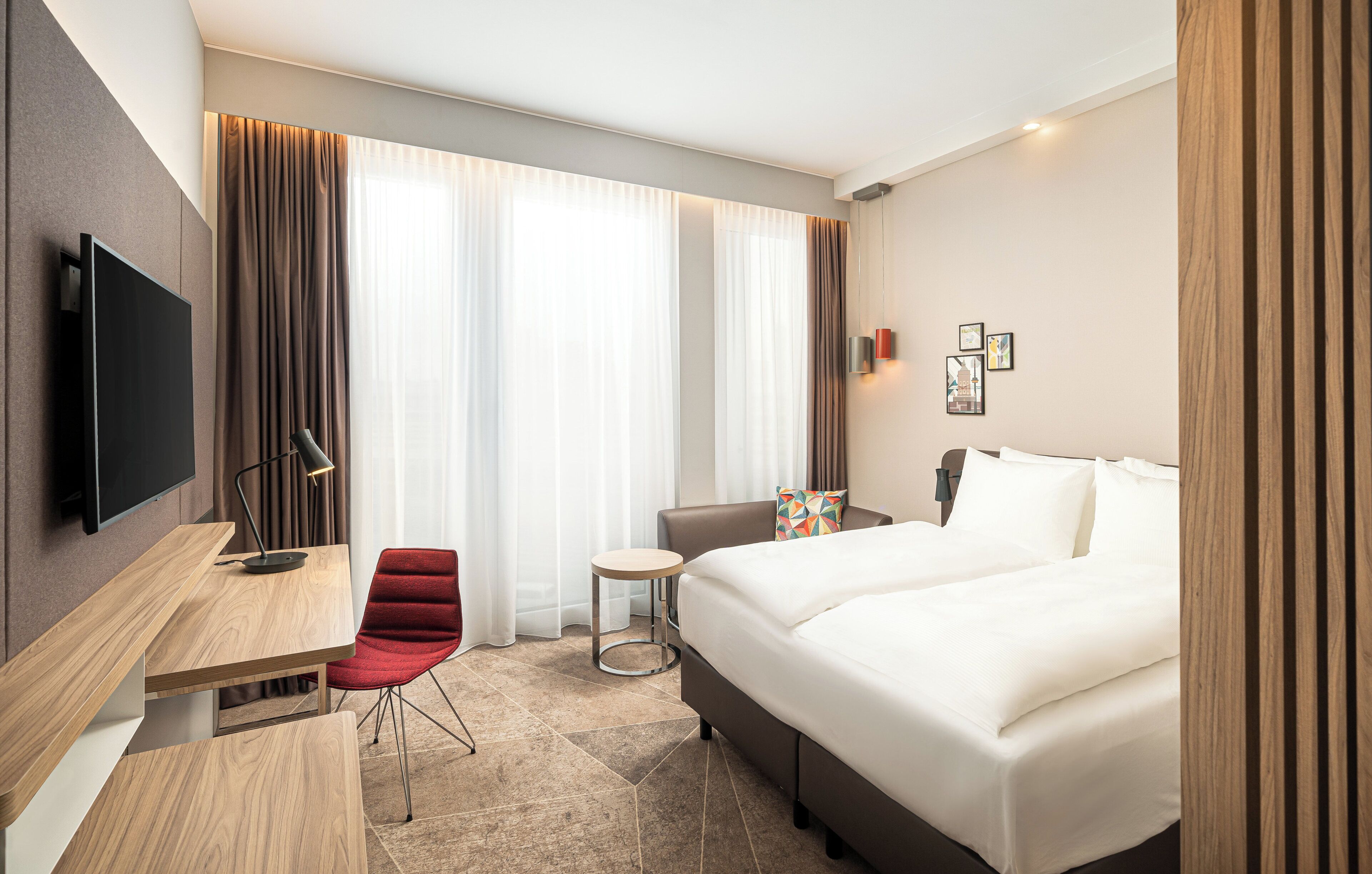 Una habitación de hotel con una cama, un escritorio, una silla, un televisor y una mesita.