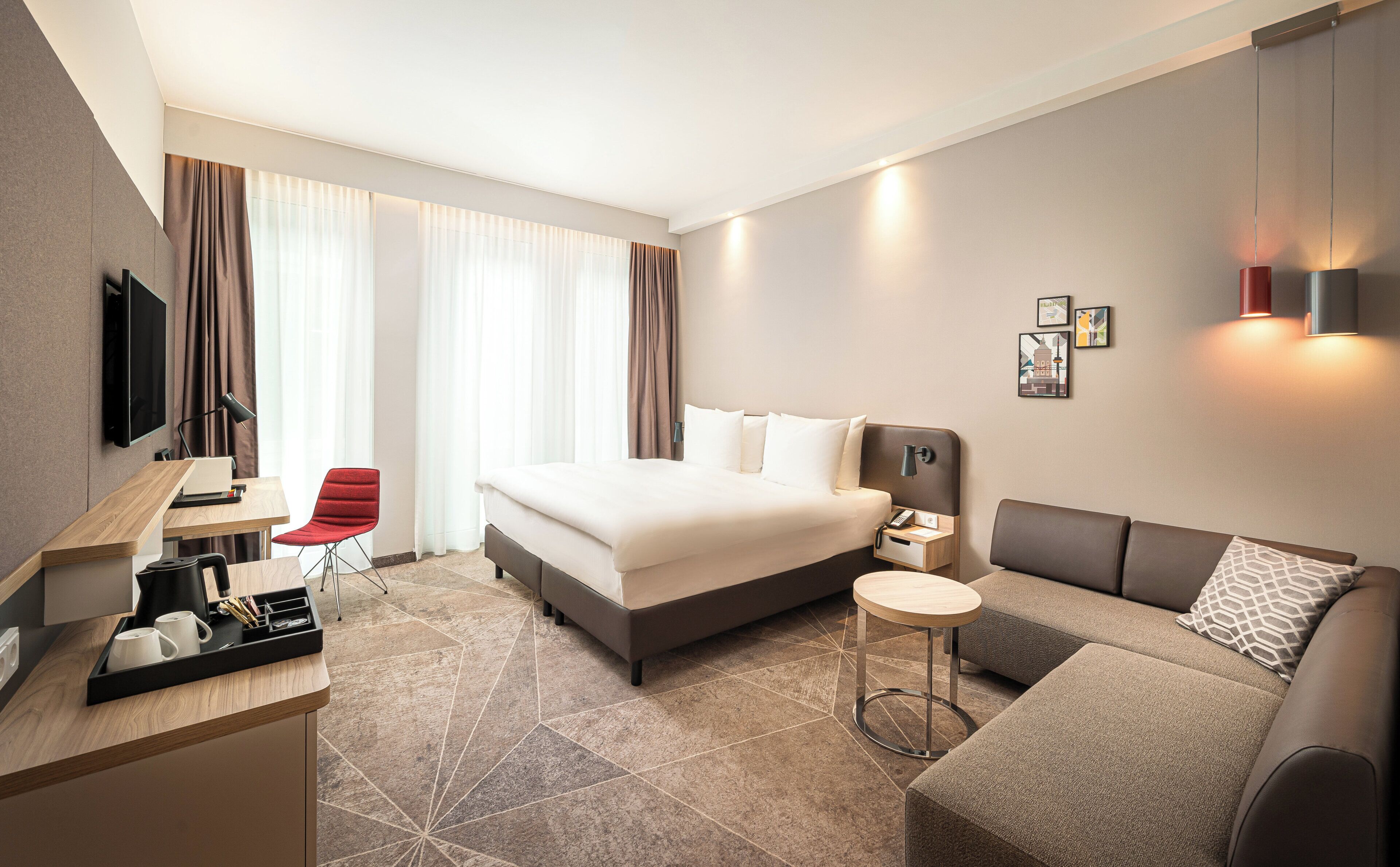 Una moderna camera d'albergo con un letto, una scrivania, una sedia, un divano e una televisione.