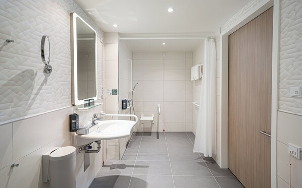 Un baño moderno con un espejo grande, dos lavamanos, un inodoro y una zona de ducha.