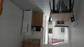 A compact kitchen with a refrigerator, microwave, and wooden cabinets. - Studio apartment in a condominium with air conditioning. (Curitiba)