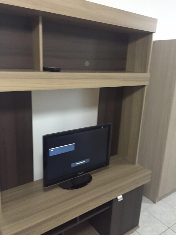 A flat-screen TV on a wooden entertainment unit with shelves.