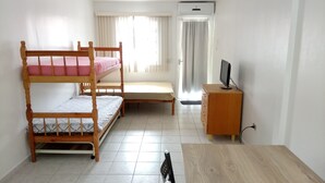 A room with a bunk bed, a desk, a chair, and a television. - Studio apartment in a condominium with air conditioning. (Curitiba)