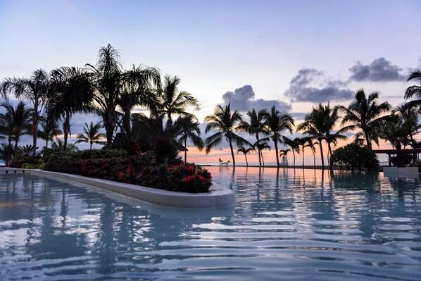 Une piscine bordée de palmiers, avec une vue imprenable sur le coucher de soleil.