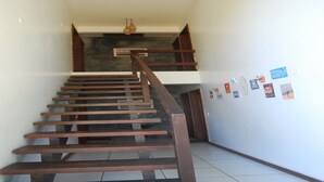 A wooden staircase leading to an upper floor, with a tiled floor and a wall decorated with small pictures. - Bahia Bonita Flat (Itacaré)