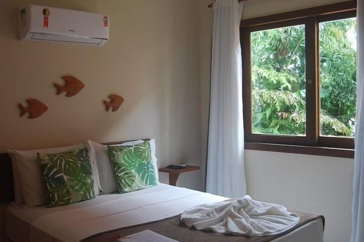 Une chambre à coucher avec un lit, un ventilateur de plafond, une fenêtre avec des rideaux et un climatiseur fixé au mur.