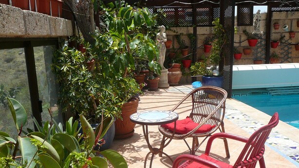 Ein Patio-Bereich mit Korbstühlen, einem kleinen runden Tisch und Topfpflanzen.