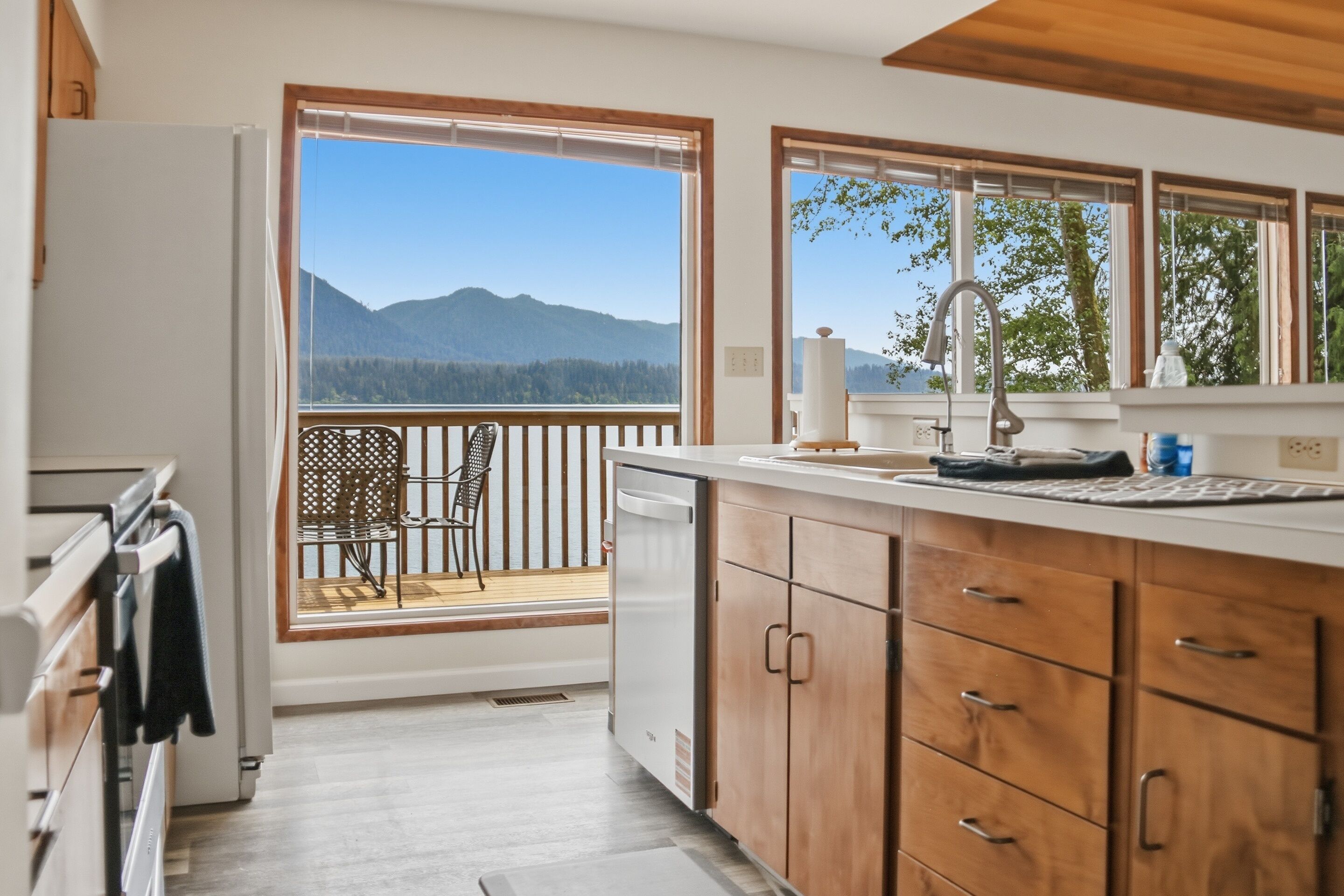 A kitchen with wooden cabinets, a white refrigerator, and a view of mountains through large windows.