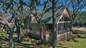 A wooden house with a green roof, a porch, and a lattice railing. - Sound View, Pet Friendly Home in Harkers Island, NC (Core Sound Lodge) (Harkers Island)