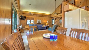 A wooden dining area with a large table, chairs, and a refrigerator. - Sound View, Pet Friendly Home in Harkers Island, NC (Core Sound Lodge) (Harkers Island)