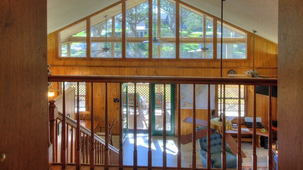 A spacious loft with a high ceiling, large windows, and a view of the backyard. - Sound View, Pet Friendly Home in Harkers Island, NC (Core Sound Lodge) (Harkers Island)