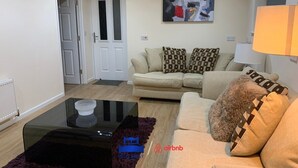 A living room with a sofa, a coffee table, and a painting on the wall.