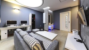 A modern living room with a sofa, a coffee table, a TV, and a desk with two monitors. - Urban Stay (Gwangju)