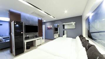Una habitación de hotel moderna con una cama grande, un televisor de pantalla plana, un escritorio con una computadora, un espejo y una ventana con vista a la ciudad.