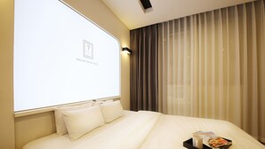 A hotel room with a large bed, a projector screen, and a window with curtains. - Urban Stay (Gwangju)