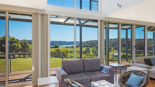 A spacious room with large windows offering a view of a lake and greenery. - Bayview Ringlands - Enjoy this relaxing escape (Narooma)