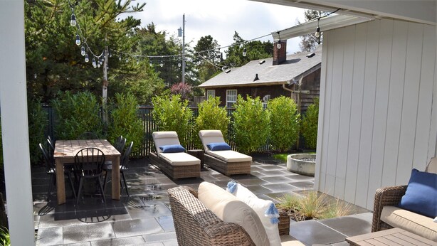 A patio with wicker furniture, a table, and chairs. - Super Comfy 3 Bed Home, Lovely Patio and Yard with Upscale Seating and Beautiful (Seaside)