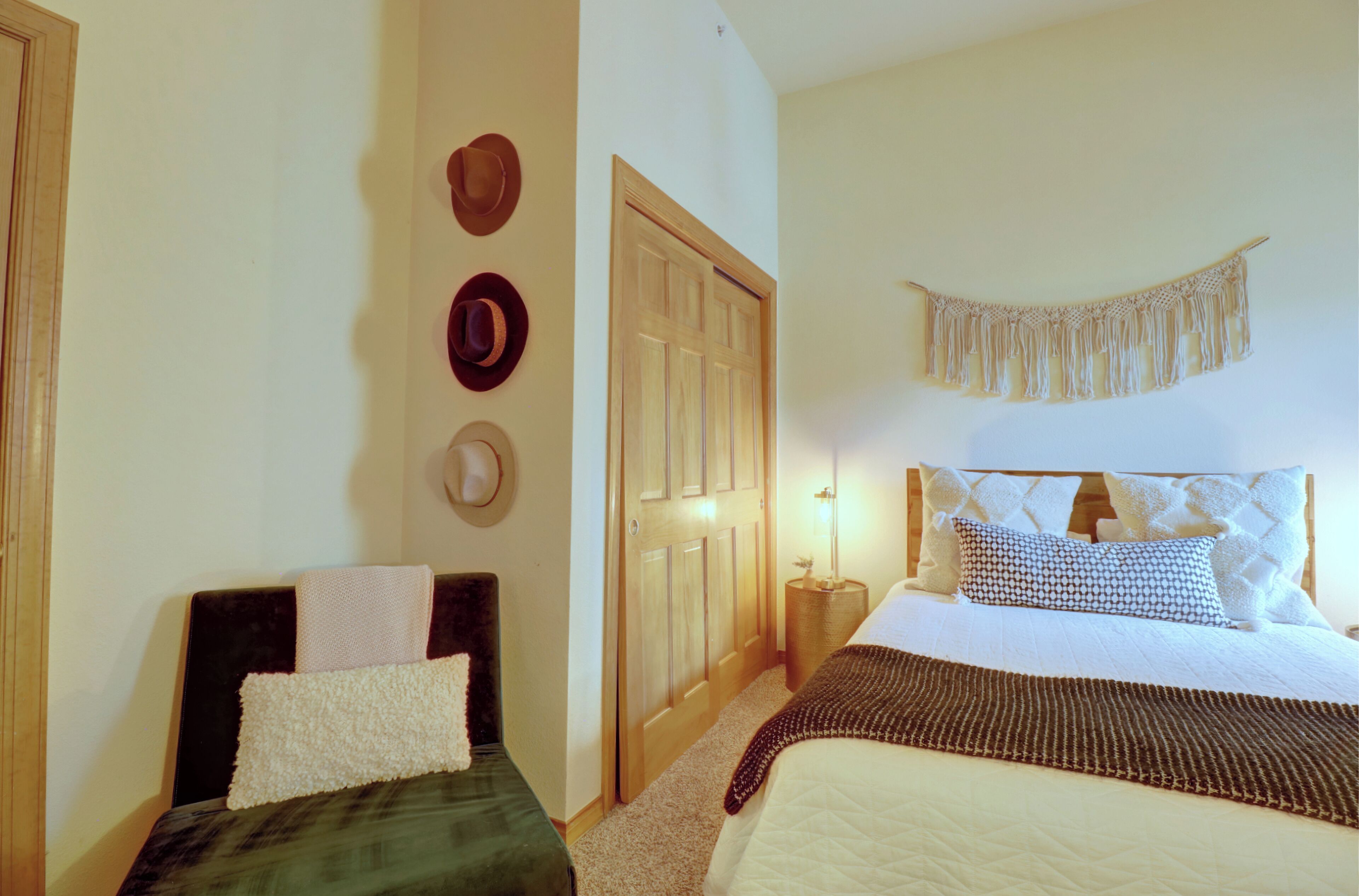 A bedroom with a bed, bedside tables, a wardrobe, and a wall-mounted macrame piece.