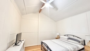 A bedroom with a bed, bedside table, lamp, and a ceiling fan. - JJ s Holiday House - River views and ocean breezes await (WOOLI)