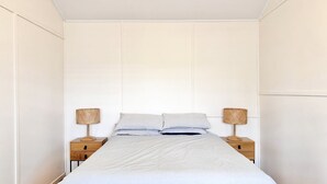 A bedroom with a bed, two bedside tables, and two lamps. - JJ s Holiday House - River views and ocean breezes await (WOOLI)
