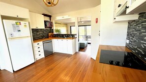 Una cucina moderna con mobili bianchi, lavastoviglie integrata e uno schienale nero.