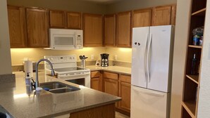 Una cocina con armarios de madera, un refrigerador blanco, un microondas, una estufa y una cafetera.