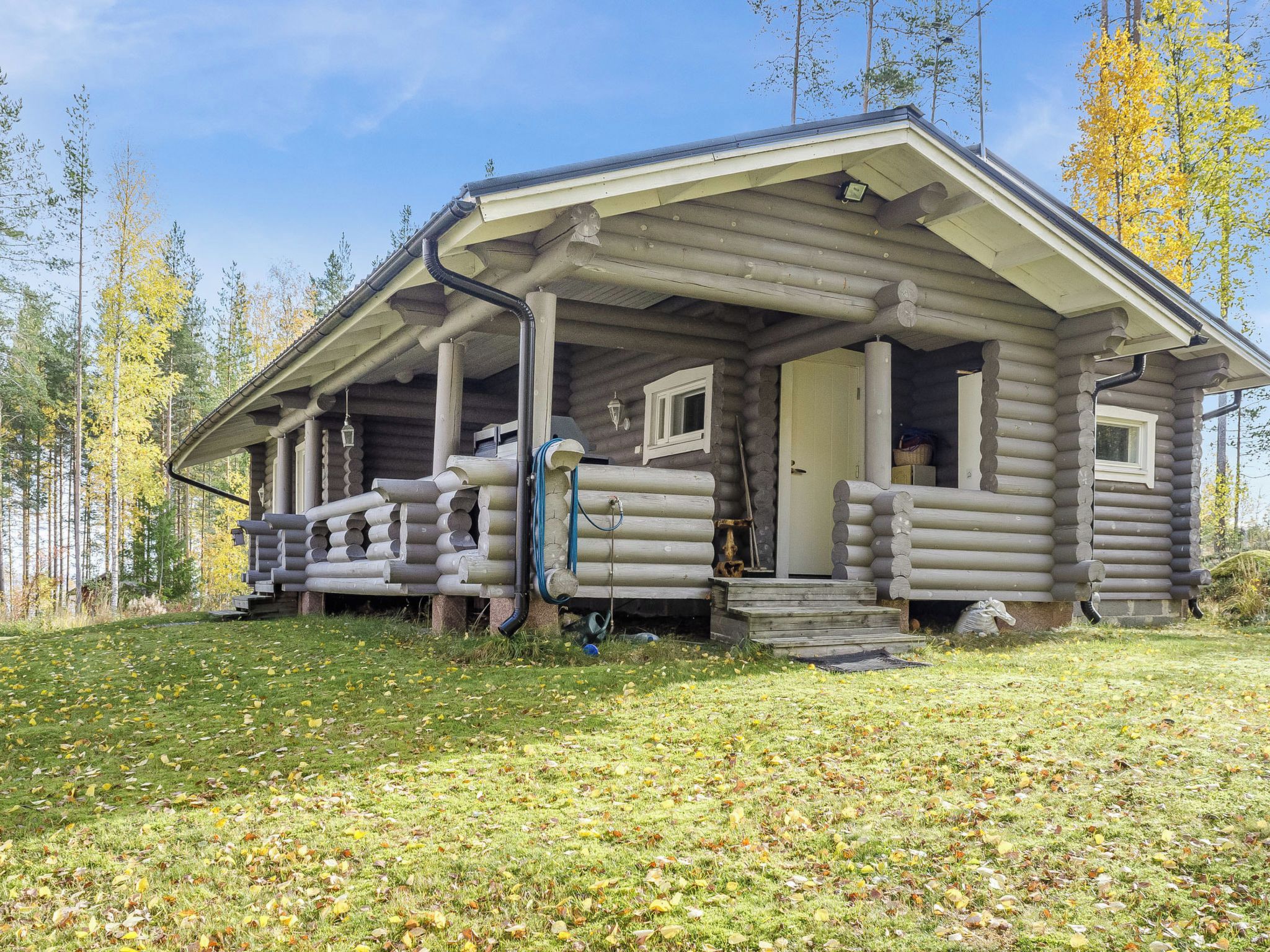 Une cabane en rondins dotée d’une véranda, d’une cheminée et d’une porte donnant sur l’intérieur.