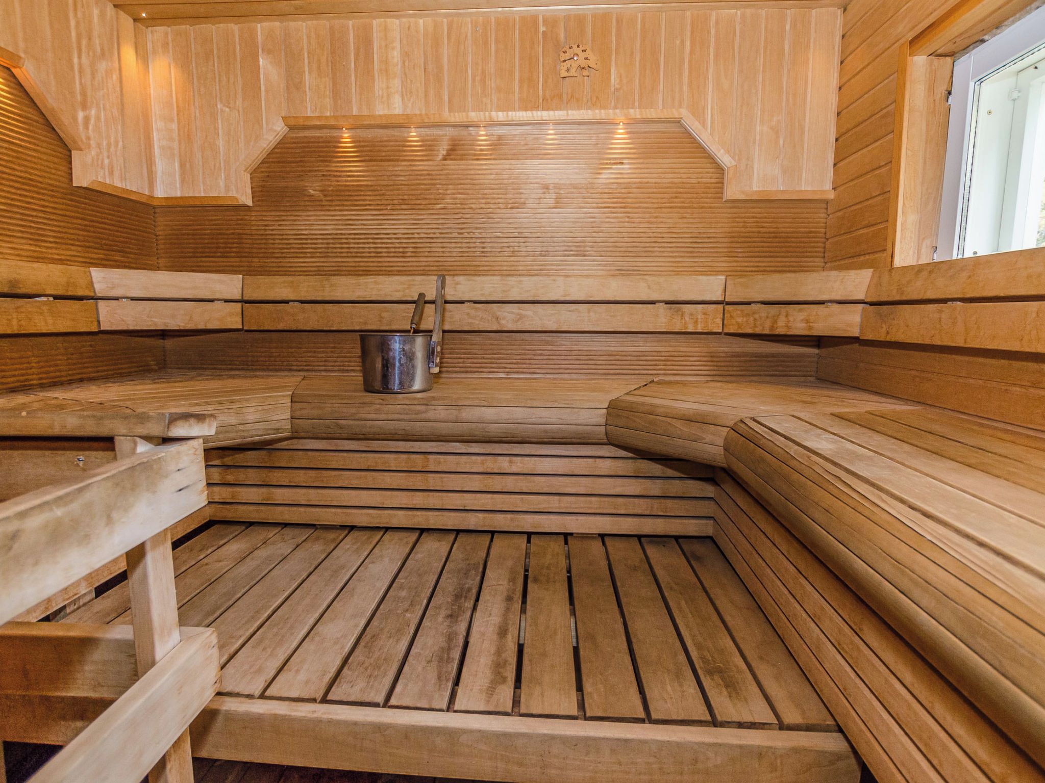 Una sauna con bancos de madera y un balde de metal.