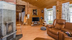 Un salon chaleureux avec une cheminée, un canapé en cuir et un téléviseur.