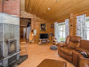 A cozy living room with a fireplace, leather sofa, and a television. - Markenniemi by Interhome (Joensuu)