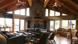 A spacious living room with a stone fireplace, leather furniture, and large windows. - Luxury Ranch Compound on 300 acres, just outside Galena Territory. 30 bedrms. (Elizabeth)