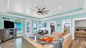 A spacious living room with a large sectional sofa, a ceiling fan, and a television. - 3 BR●2.5 BA●Cargo Lift●Fire Pit●Dog Friendly●Horse Boarding Nearby (Crystal Beach)